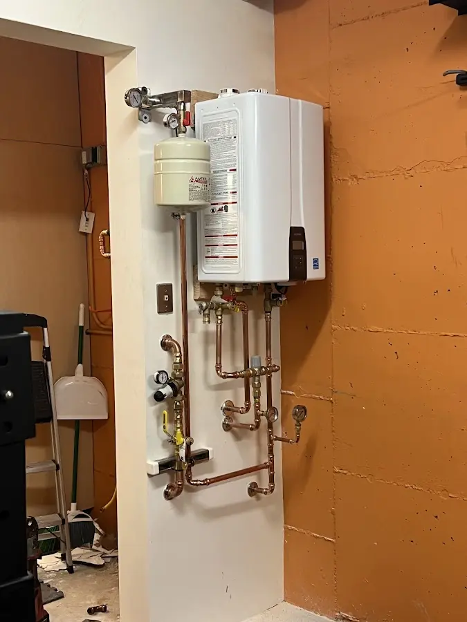 Plumbing technician inspecting water heater connections in Tinton Falls